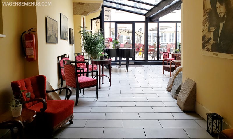 Hotel romântico em Praga - entrada do Hotel Leonardo, cadeiras clássicas com estofado vermelho, um piano, quadros na parede