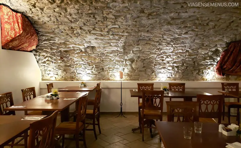 Hotel Leonardo - restaurante do café da manhã, paredes de pedra, mesas de madeira e luz baixa