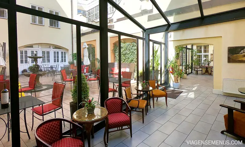 Hotel romântico em Praga: pátio do Hotel Leonardo, com cadeiras clássicas de estofado vermelho e plantas
