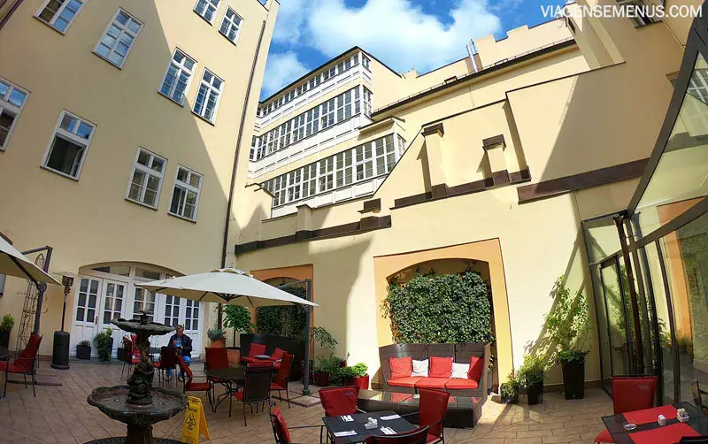 Hotel romântico em Praga: pátio que conecta os quatro prédios do Hotel Leonardo, com cadeiras, sombrinha e uma fonte