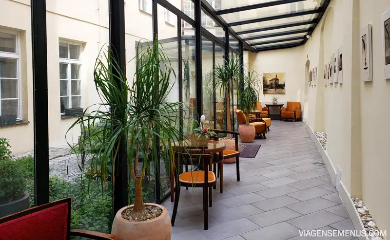 Hotel romântico em Praga: jardim interno do hotel, com cadeiras de madeira e mesinhas