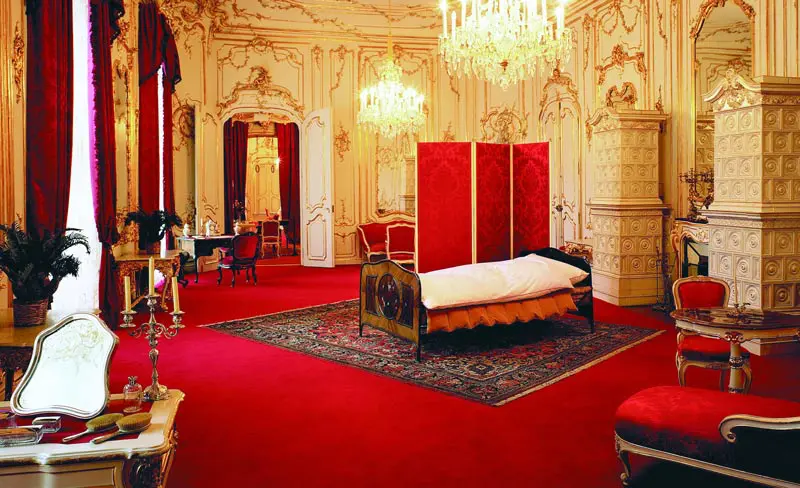 Palácio de Hofburg - Apartamentos Imperiais - quarto da Sisi com tapete vermelho, lustres e objetos de ouro