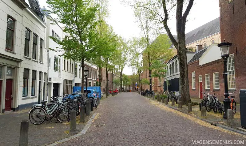 O que fazer em Utrecht, Holanda  - rua tranquila de paralelepípedo, prédios típicos holandeses de até 3 andares nos tons marrom e branco, árvores e bicicletas estacionadas na esquina.