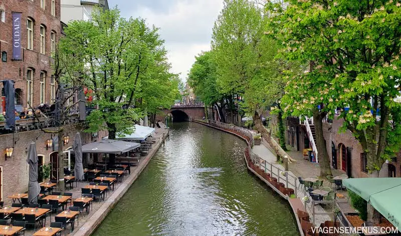 O que fazer em Utrecht, Holanda - paisagem com um canal de Utrecht, restaurantes, prédios históricos e muitas árvores nas duas margens.