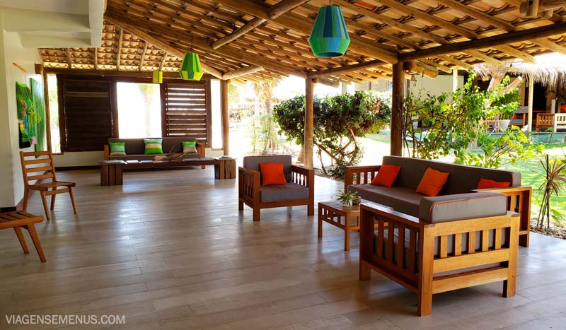 Hotel Vila Selvagem, Fortim, Ceará - ambiente interno do hotel, um salão com sofás e mesinhas, tudo na madeira com almofadas vermelhas e verdes