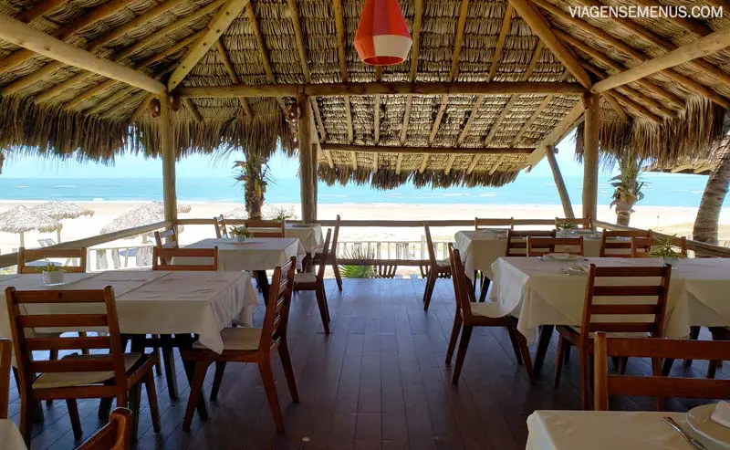 Hotel Vila Selvagem, Fortim, Ceará - mesas e cadeiras de madeira, mesas com toalhas brancas, teto de palhoça, vista para o mar