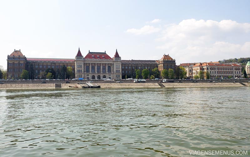 Passeio de barco em Budapeste - algumas construções nas margens do Danúbio, um prédio bonito como um palácio de paredes mármore e teto vermelho