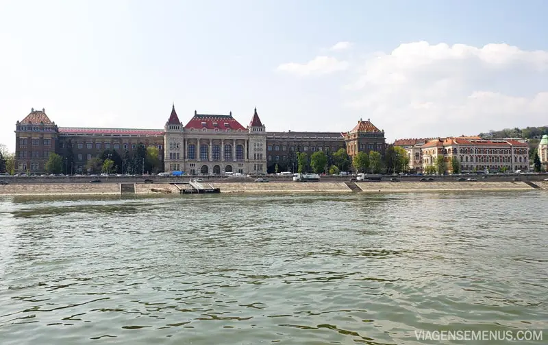 Passeio de barco em Budapeste - algumas construções nas margens do Danúbio, um prédio bonito como um palácio de paredes mármore e teto vermelho