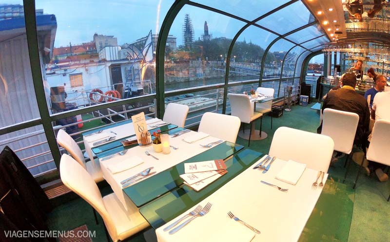 Passeio de barco em Budapeste - interior do barco de jantar da Legenda Cruises, com várias mesas de vidro e cadeiras brancas