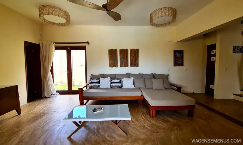 Vila Harmonia, Praia do Preá - imagem da sala, com um sofá grande bege, uma mesa branca e 3 quadros