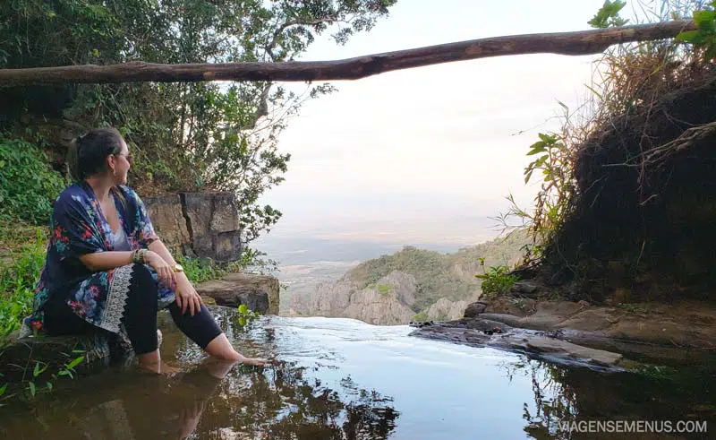 Livia olhando paisagem sentada na borda de uma cachoeira - Ubajara, Chapada da Ibiapaba, o que fazer no Ceará
